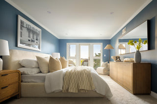 Modern bedroom with blue walls, wooden furniture, and a large bed.
