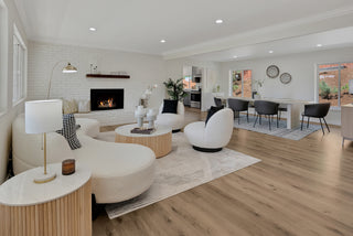 Modern living room with white furniture, fireplace, and kitchen in the background.