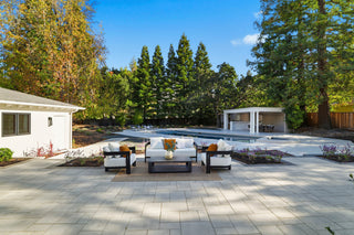 A backyard featuring patio furniture arranged around a swimming pool, creating a relaxing outdoor space.