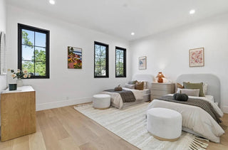 A bedroom featuring two beds against a plain white wall, creating a simple and spacious atmosphere.