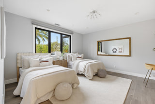 A bedroom featuring two beds and a large mirror reflecting the rooms decor and layout