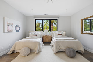 A bedroom featuring two beds positioned near a window, allowing natural light to fill the space.