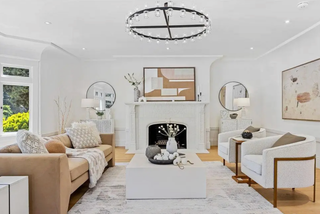 Modern living room with beige sofa, white armchair, and fireplace.