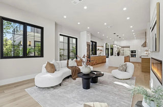 A bright living room featuring white furniture and warm wood floors, creating a cozy and inviting atmosphere