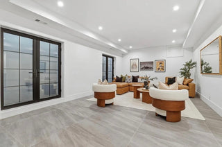 A bright living room featuring white walls and flooring, creating a spacious and airy atmosphere.
