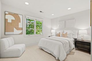 Modern bedroom with a bed, chair, and abstract art on the wall.