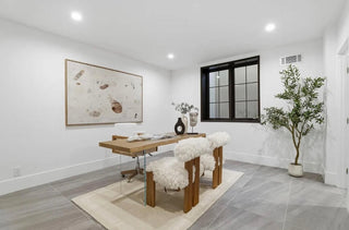 A bright white room featuring a wooden desk and a colorful painting on the wall.