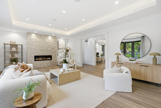 A clean living room featuring white furniture and a cozy fireplace, creating a bright and inviting atmosphere