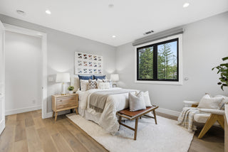 A cozy bedroom featuring a bed, a chair, and a window allowing natural light to enter the space