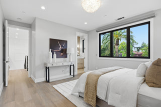 A cozy bedroom featuring a bed, a nightstand, and a window allowing natural light to enter the space