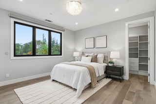 A cozy bedroom featuring a bed, a window allowing natural light, and a soft rug on the floor