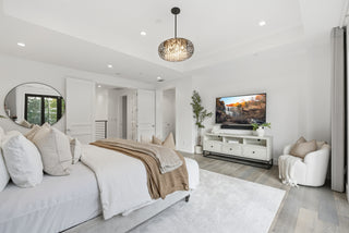 A cozy bedroom featuring a large bed and a flat-screen TV mounted on the wall