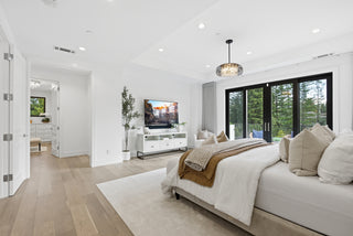 A cozy bedroom featuring a large bed and a flat-screen television on the wall