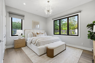 A cozy bedroom featuring a white bed and an elegant chandelier hanging from the ceiling