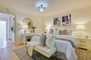 Neatly arranged bedroom with a bed, seating area, and decor.