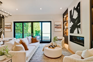 Modern living room with white sofa, ottoman, and abstract art on wall.