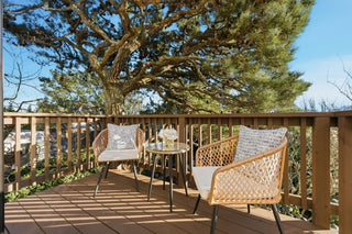A deck featuring two wicker chairs and a small table, creating a cozy outdoor seating area.