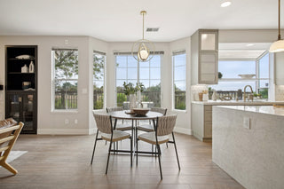 A_dining_area_with_a_round_table_four_chairs_and_a_centerpiece._Large_windows_offer_natural_light_and_a_scenic_view_creating_an_airy_ambiance.