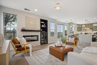 Modern living room with fireplace, furniture, and large windows.
