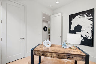 Modern office with wooden desk, computer monitor, and abstract horse artwork on wall.