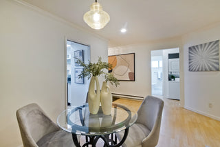 Modern dining room with glass table, chairs, and decorative elements.