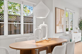 Modern dining room with wooden table, white chairs, and decorative elements.