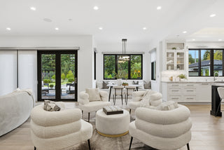 A modern kitchen and living room featuring sleek white furniture and an open layout, creating a bright and airy atmosphere.