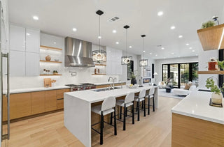 A modern kitchen featuring white cabinets and warm wooden floors, creating a bright and inviting atmosphere.