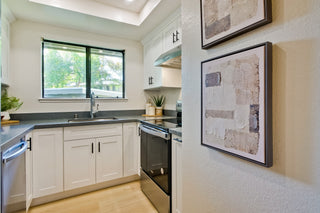 Modern kitchen with white cabinets, black countertops, and framed artwork on the wall.