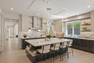 A modern, minimalist dining table light walls and wooden flooring, abstract art on the wall, gray couch, and large windows. Cozy and bright.