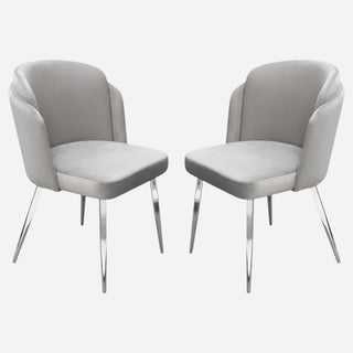 A pair of gray velvet dining chairs with chrome legs.
