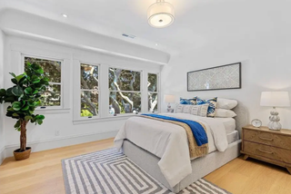 Modern bedroom with a bed, nightstands, and large windows.
