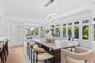 Modern dining room with a long table and chairs, large windows, and decorative elements.