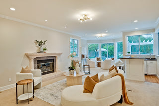 Modern living room with white furniture, decorative pillows, and large windows.