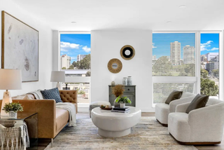 Modern living room with large windows, stylish furniture, and decorative elements.