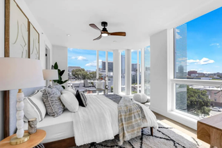 Modern bedroom with large windows offering a cityscape view.