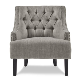 A textured taupe fabric upholstered accent chair with high-polish nailhead trim, a button-tufted back, and black finish wood legs.