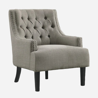 A textured taupe fabric upholstered accent chair with high-polish nailhead trim, a button-tufted back, and black wood legs.