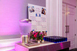 Event setup with floral arrangement, blue cups, and informational poster on a table.
