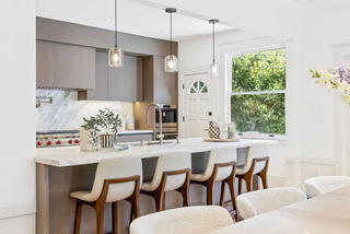 Modern kitchen with island and chairs, featuring a kitchen counter and appliances.