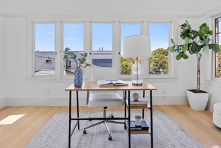 Home office with a desk, chair, and large windows overlooking trees.