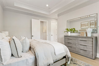 Modern bedroom with gray dresser, mirror, and bed with white bedding.
