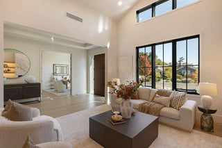 Advance living room with large windows, neutral decor, and a coffee table nice feature view from glass