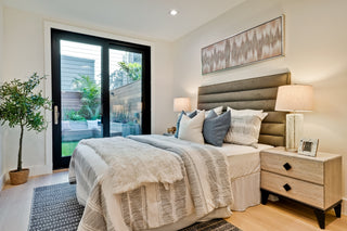Modern bedroom with a bed, nightstands, and a sliding glass door leading to an outdoor area.
