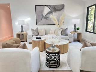 Attractive living room with white sofas, decorative pillows, and a round coffee table with a plant.  creating a serene