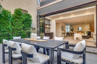 Outdoor dining area with a table and chairs in front of a modern house.