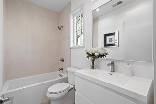 Bathroom with white fixtures, a bathtub, and a sink with a mirror.