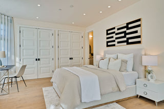 Modern bedroom with a bed, nightstands, and artwork on the wall.