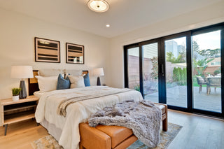 Modern bedroom with a bed, nightstands, and a sliding glass door leading to an outdoor area.