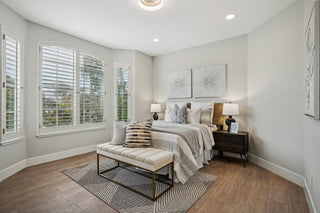 Bedroom_a_large_bed_with_layered_textiles_a_striped_upholstered_bench_and_plantation_shutters